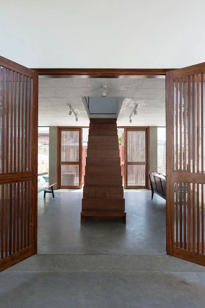 Kiến trúc sư thiết kế cầu thang bằng gỗ ngay lối cửa chính vào nhà.