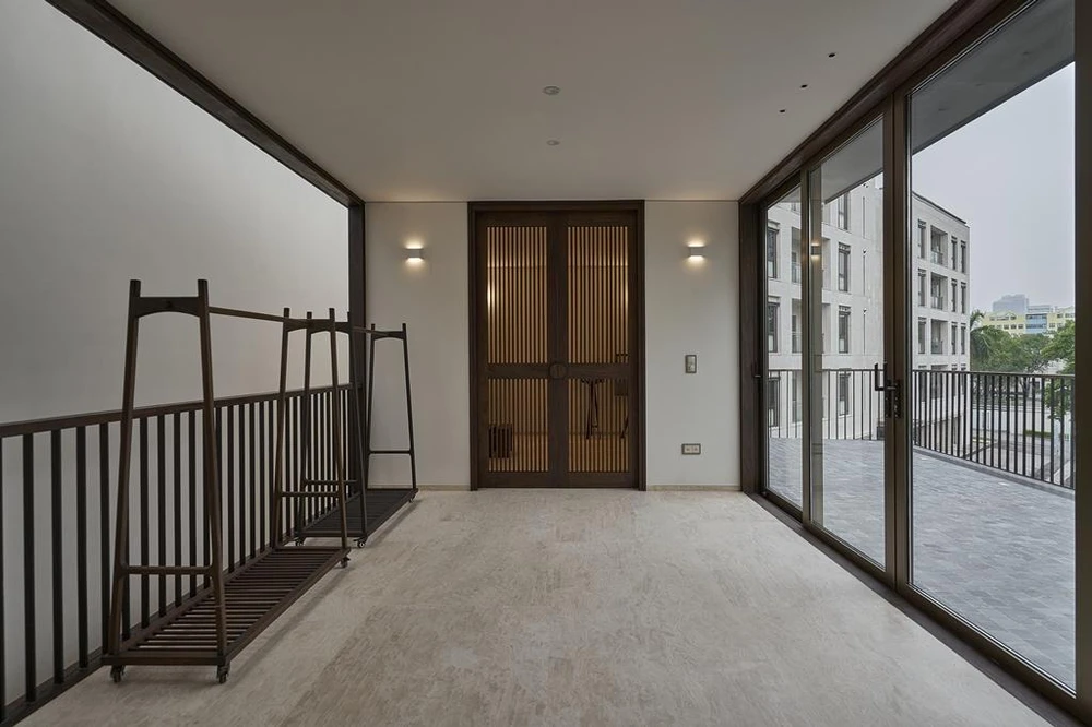 Ngôi nhà như đang nép mình sau những tán cây, tạo ra một bầu không khí riêng tư hoàn toàn đối lập với bối cảnh hoạt động dịch vụ tấp nập xung quanh.