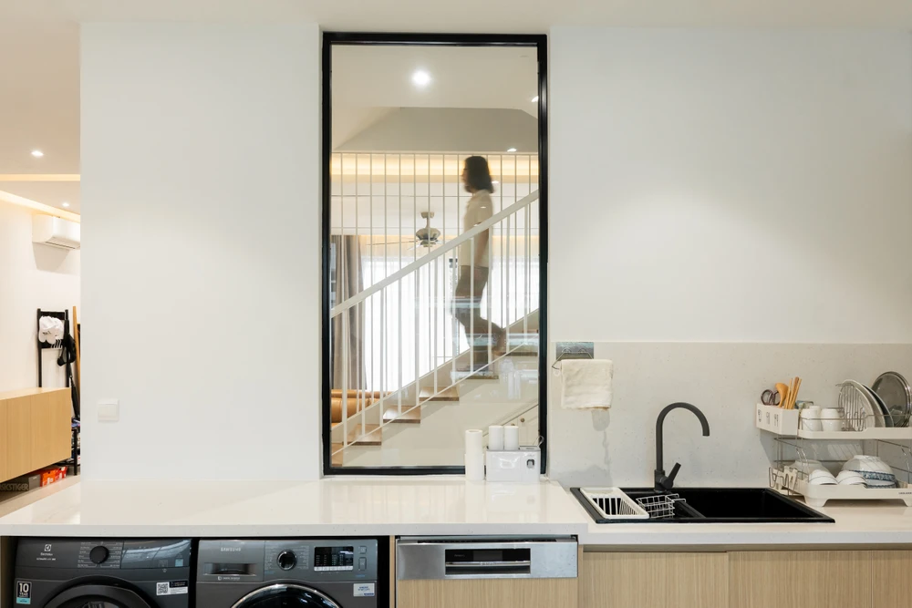 Để không gian được liên tục, từ khu vực phòng khách có thể nhìn thấy phòng bếp, kiến trúc sư thiết kế thêm ô cửa kính.