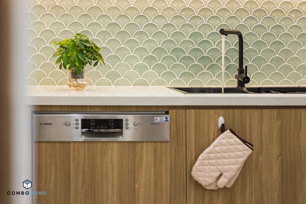 Căn hộ sử dụng các thiết bị bếp tiện nghi, ốp tường bếp hình vảy cá màu xanh mềm mại.