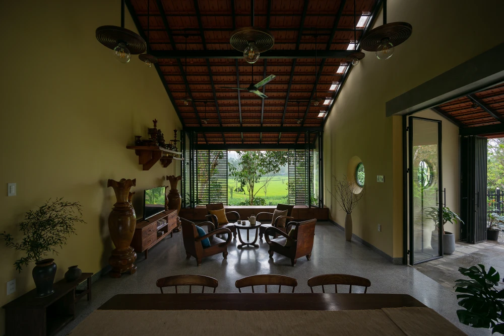 Nhà Tiên Cẩm có diện tích 170 m2 nằm trên một đồi dốc, dưới chân là vườn cây ăn trái và một con suối chảy dài bên cạnh cánh đồng lúa xanh mướt.