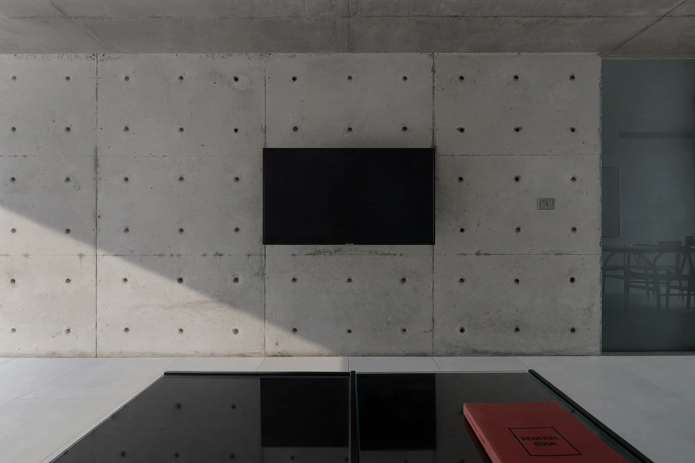 Nhằm đảm bảo không gian riêng tư, kiến trúc sư thiết kế phòng làm việc, phòng ngủ và phòng vệ sinh được ngăn cách với không gian sống bằng bức tường bê tông cao 2,2 m.