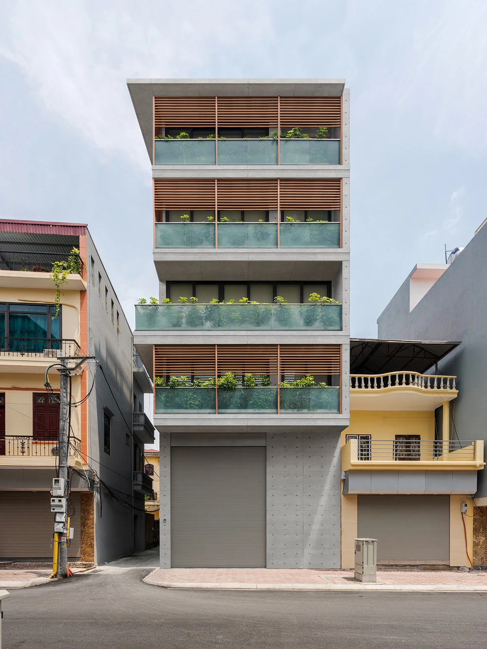 Diện mạo mặt đứng bên ngoài ngôi nhà trải dài là một hệ ban công cây xanh và lam gỗ. Hệ ban công này tạo sự ngăn cách ước lệ giữa bên ngoài và bên trong.