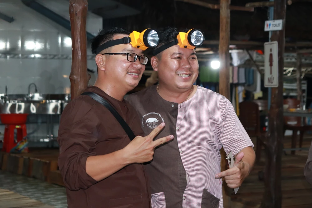 Du khách mặc áo bà ba, trang bị bao tay, đội đèn pin để vào rừng soi ba khía. 