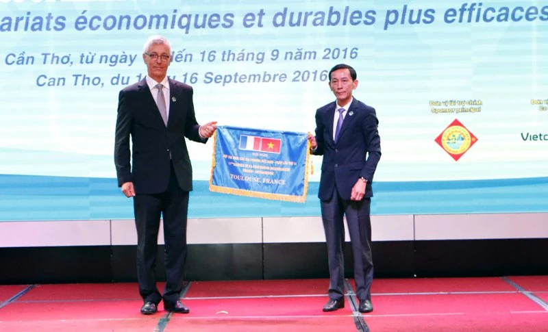 Chủ tịch UBND TP Cần Thơ Võ Thành Thống (bìa phải) trao cờ đăng cai Hội nghị lần thứ 11 cho đại diện TP Toulouse 
