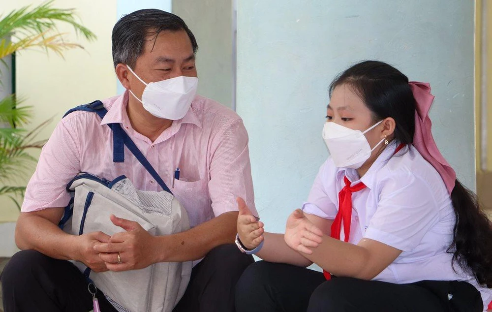 Cha và con gái cùng trò chuyện sau khi con đã tiêm xong. Ảnh: CHÂU ANH