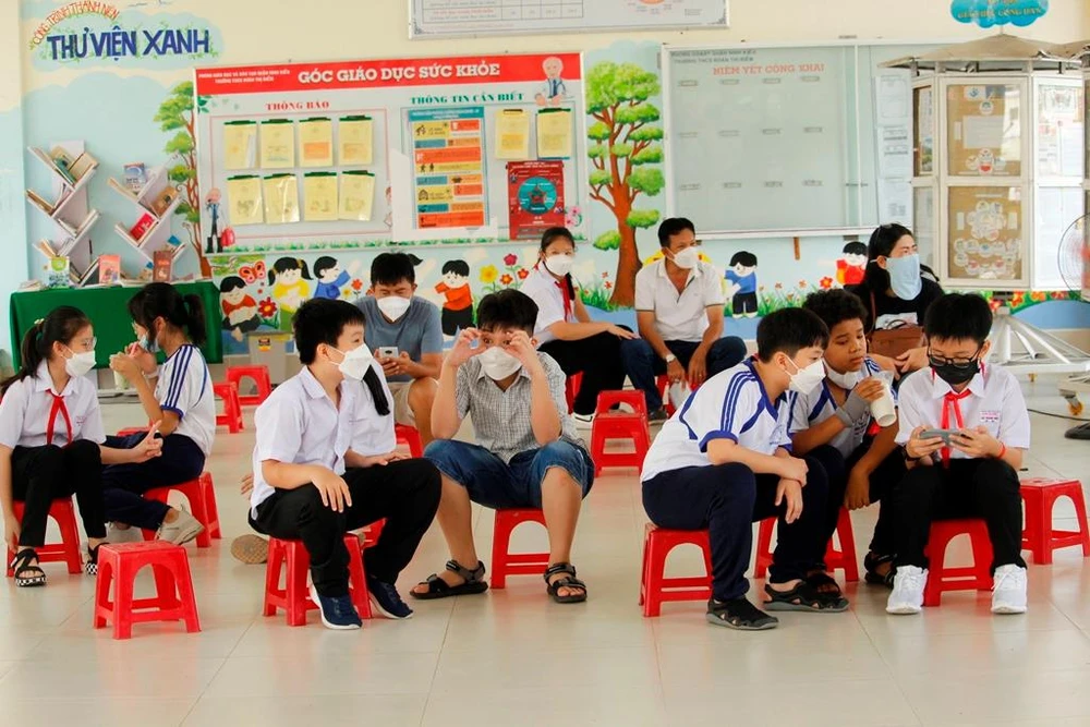 Khu vực theo dõi sau tiêm, các bạn thoải mái tám chuyện và xem điện thoại. Ảnh: NHẪN NAM