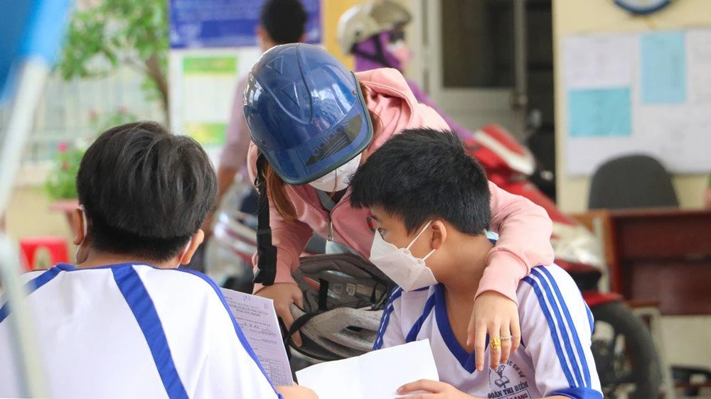 Phụ huynh cùng con chờ vào khám sàng lọc trước tiêm. Ảnh: CHÂU ANH