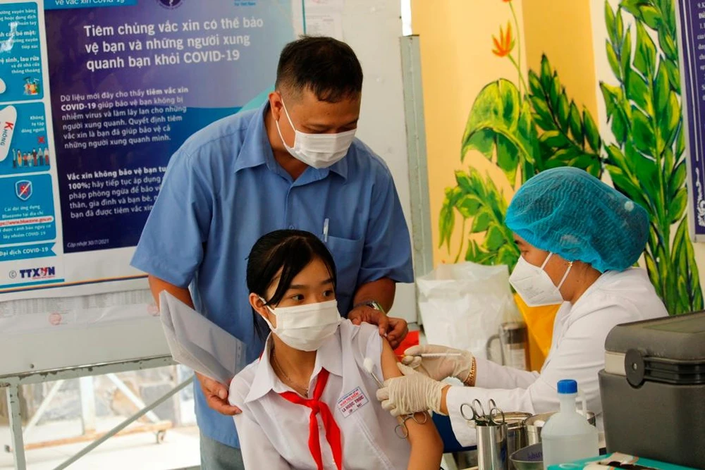 Phụ huynh hỗ trợ con khi vào tiêm phòng. Ảnh: NHẪN NAM