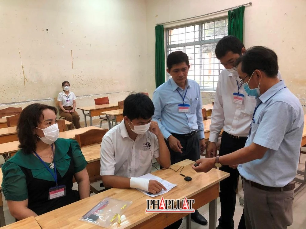 Hướng dẫn cán bộ coi thi cách thức vận hành máy ghi âm để TS làm bài. Ảnh: NHẪN NAM