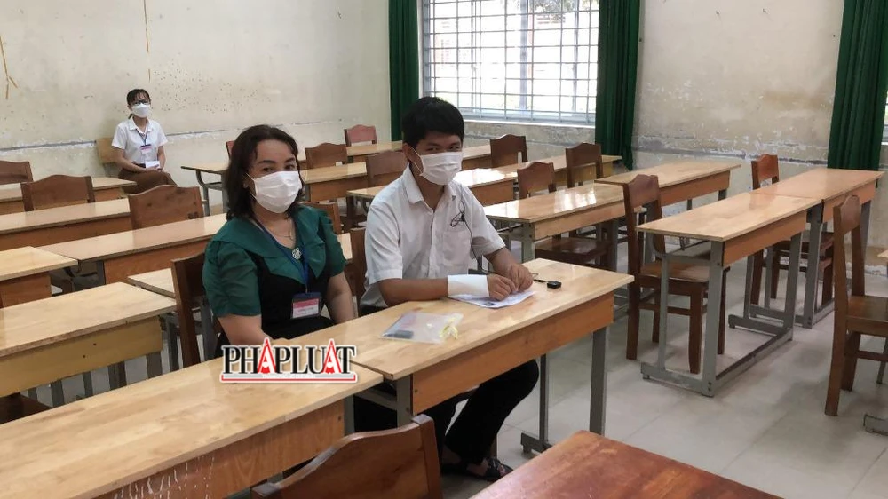 Một mình Hùng trong phòng thi làm bài với sự giám sát của hai cán bộ coi thi và một cán bộ hỗ trợ viết. Ảnh: NHẪN NAM