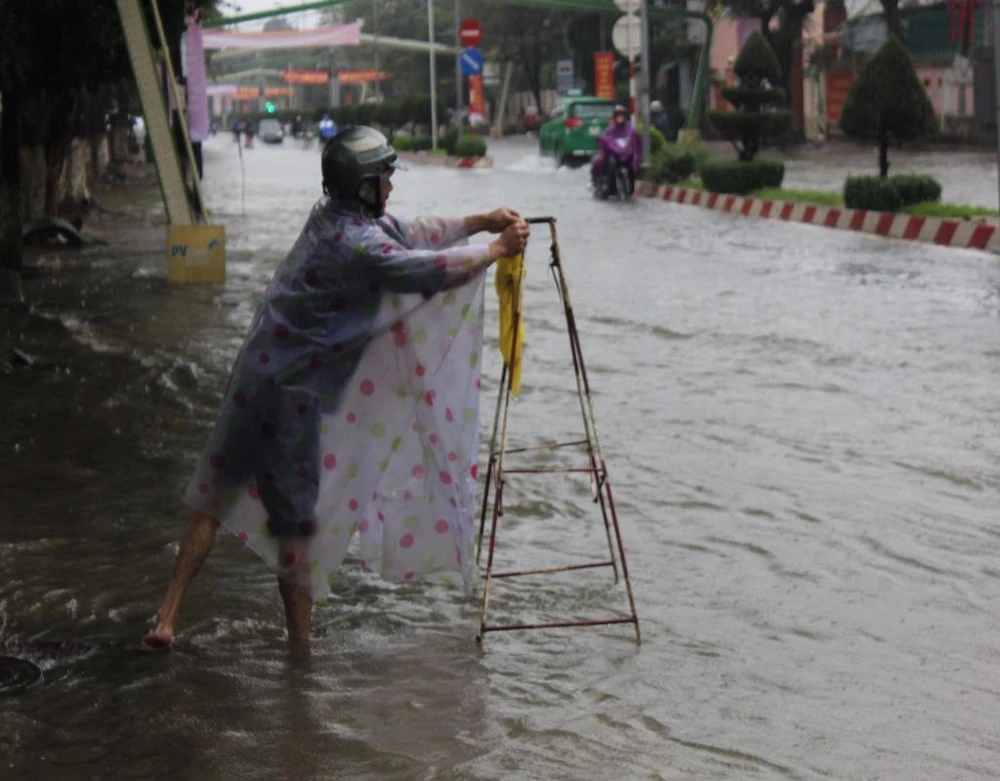Nhân viên Công ty cổ phần môi trường đô thị Quảng Ngãi tháo hố ga trên đường Hùng Vương để nước thoát nhanh hơn.