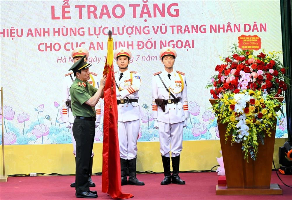 Bộ trưởng Lương Tam Quang trân trọng gắn danh hiệu Anh hùng lực lượng vũ trang nhân dân lên lá cờ truyền thống của Cục An ninh đối ngoại.
