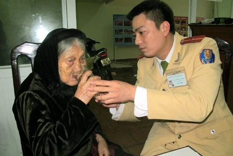 Thiếu úy Nguyễn Hiếu Minh chăm sóc cụ Lê tại trụ sở Đội CSGT số 2, chờ tìm lại nhà cho cụ.