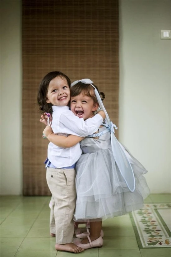 Ngay sau đó, “cô Bống” tiếp tục chia sẻ hình ảnh hiện tại vô cùng đáng yêu của hai bé Tôm và Tép ôm nhau cười tươi hạnh phúc. Trong hình, bé Tôm - Aiden (trái) mặc áo sơ mi kết hợp với quần kaki, bé Tép - Lea (phải) mặc váy công chúa màu xanh, ton-sur-ton với bờm tóc và phụ kiện cánh bướm đeo ở vai. Dù sinh đôi song Tôm và Tép có nhiều điểm khác nhau. Tôm có mái tóc đen nâu, còn cô Tép lại có mái tóc nâu vàng. Tuy nhiên, cả hai đều sở hữu đôi mắt đẹp và nụ cười rạng rỡ như thiên thần.