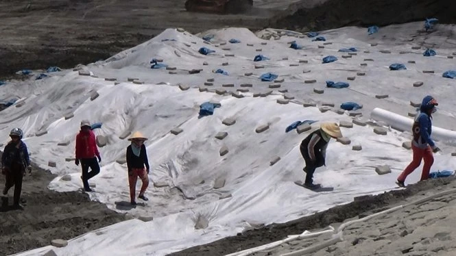 Các nhân công che phủ bạt địa kỹ thuật, ngăn chặn tình trạng gió cuốn tro xỉ bay lên tạo thành bụi - Ảnh: Nguyễn Nam