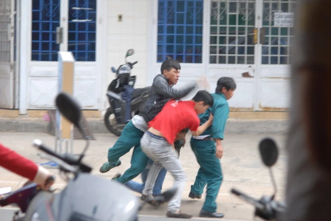 Lập tức người mặc trang phục dân quân tự vệ lao vào đánh đấm túi bụi người thanh niên mặc thường phục trước sự sửng sốt của nhiều người chứng kiến