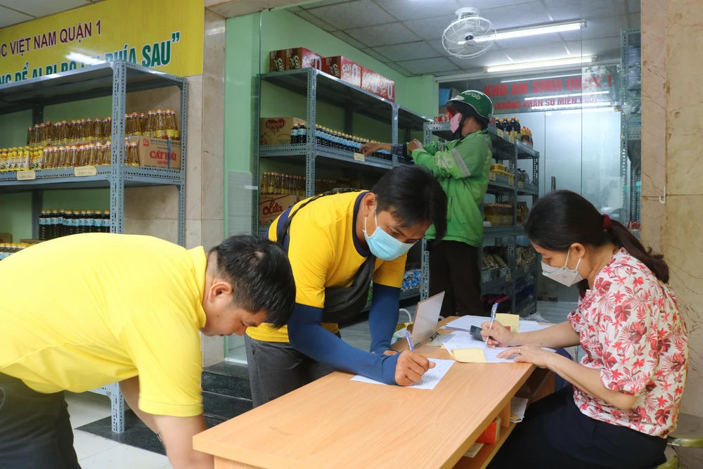 Người dân đưa phiếu đi chợ và ký tên trước khi mua hàng.
