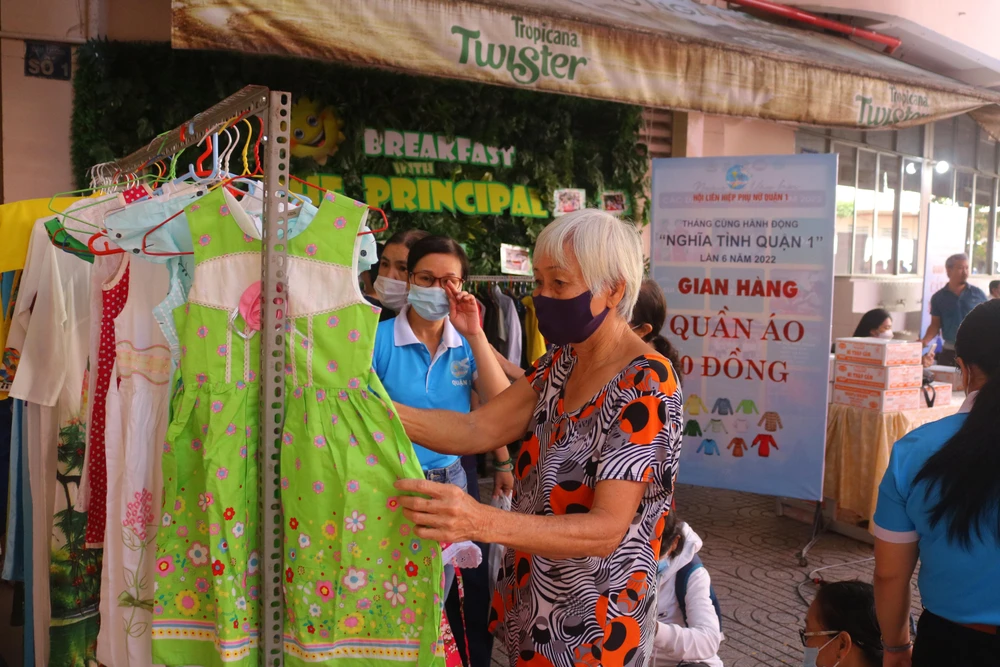 Nhận quà thuộc diện hộ nghèo xong, bà Lương Kim Hoàng, ngụ tại phường Bến Thành, ghé gian hàng quần áo 0 đồng lựa đồ về tặng cháu gái. Ảnh: NGỌC TRĂM