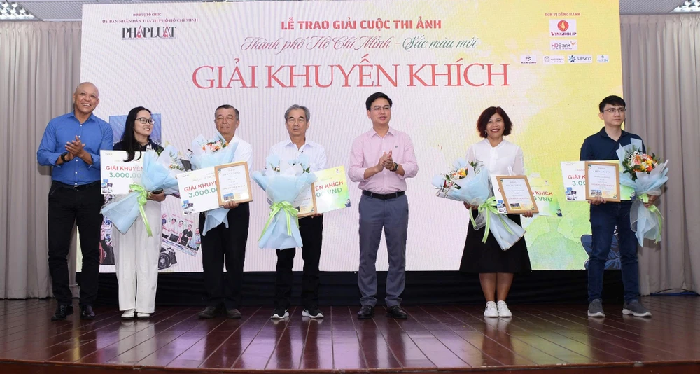 Nghệ sĩ nhiếp ảnh Nguyễn Á, Thành viên Ban giám khảo và ông Nguyễn Thanh Tùng, Trưởng Ban Kinh tế Đô Thị kiêm Phó Phòng Kinh doanh phát hành Báo Pháp Luật TP.HCM trao giấy chứng nhận cho các tác phẩm đạt giải Khuyến khích. Ảnh: TRẦN LINH