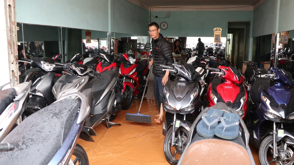 Nhân viên cửa hàng xe Thắng Lợi đang gấp rút dọn dẹp sau khi bị nước tràn vào. Ảnh CTV