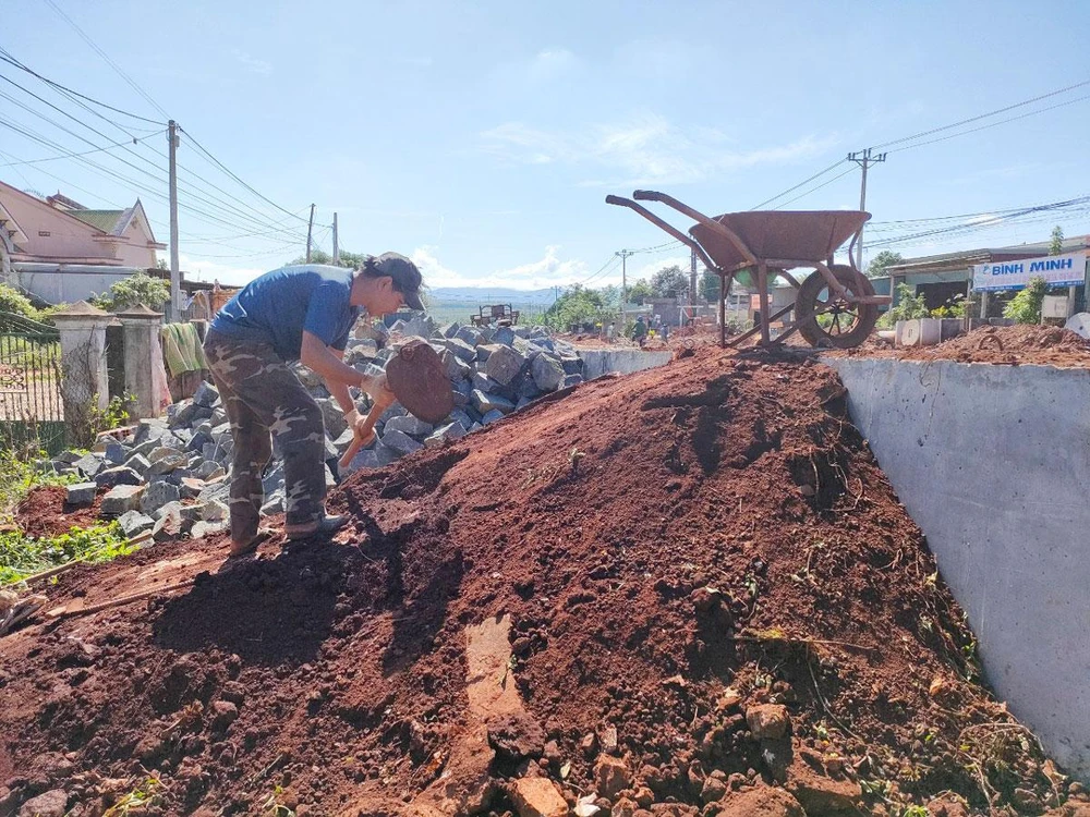 Anh Lê Anh Tú chở đất đá làm cầu tạm vào nhà vì mương nước của công trình quá cao. Ảnh: LK