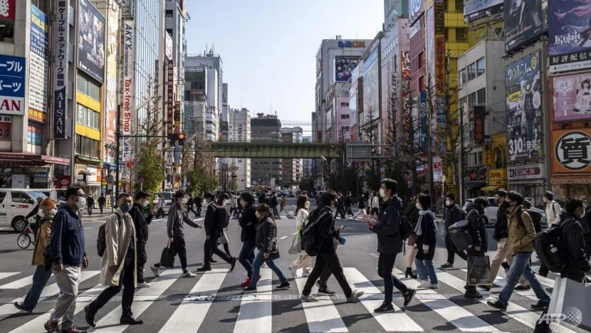 Người dân băng qua một con phố tại khu mua sắm nổi tiếng Akihabara ở Tokyo (Nhật) ngày 24-3. Ảnh: AFP