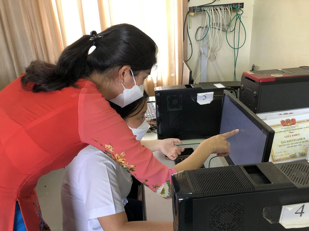 Giáo viên Trường THPT Bùi Hữu Nghĩa, TP Cần Thơ hướng dẫn học sinh đăng ký dự thi trực tuyến tại trường. Ảnh: NHẪN NAM