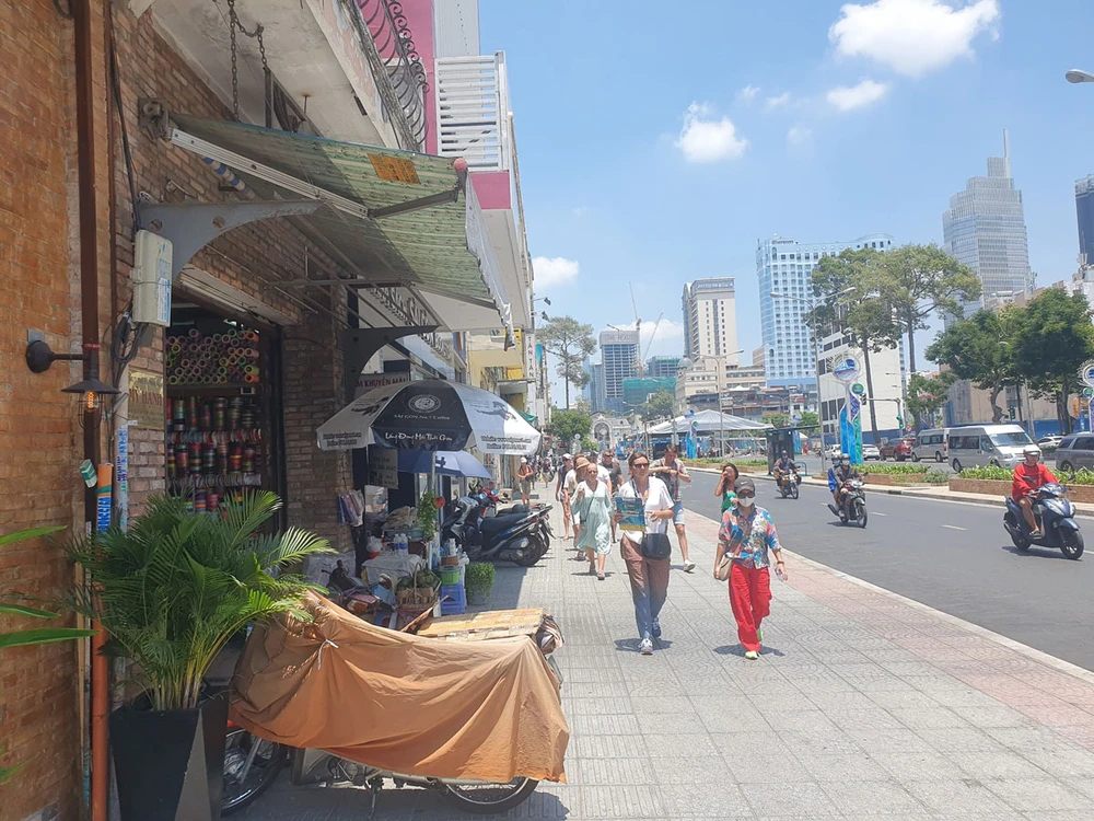 Du khách đi bộ trên vỉa hè đường Lê Lợi dưới cái nắng gay gắt vào trưa 26-3. Ảnh: KIÊN CƯỜNG