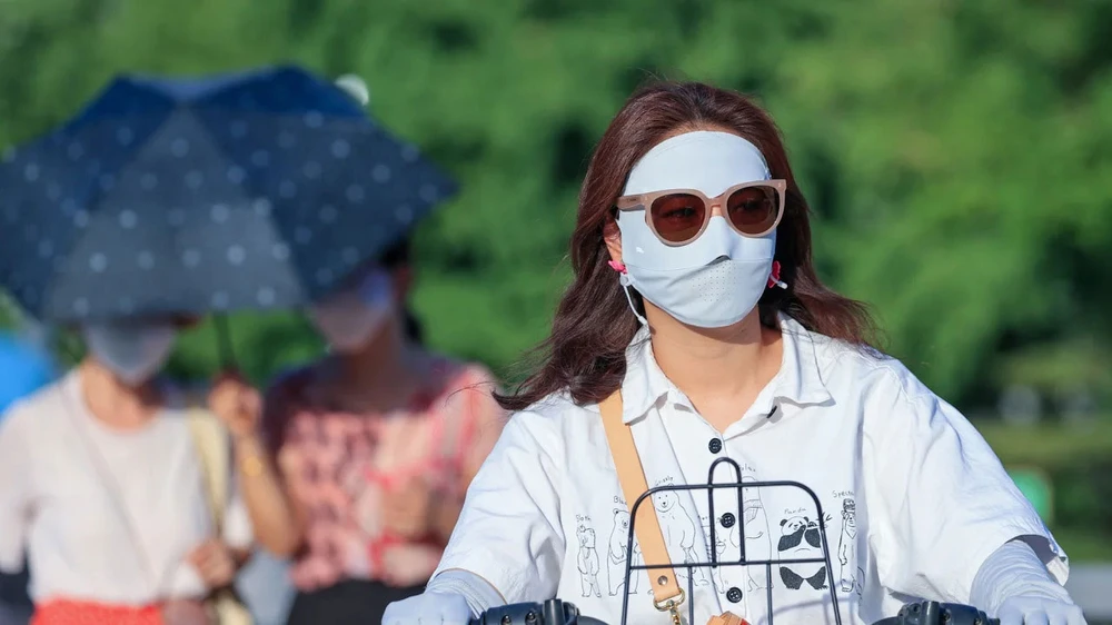 Người dân che chắn giữa cái nóng khắc nghiệt ở Bắc Kinh (Trung Quốc) vào ngày 5-7. Ảnh: GETTY IMAGES