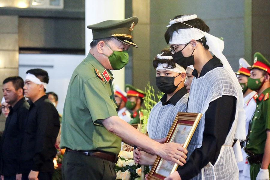 Bộ trưởng Bộ Công an - Đại tướng Tô Lâm trao huân chương Chiến công và bằng Tổ quốc ghi công cho thân nhân ba liệt sĩ cảnh sát PCCC Hà Nội. Ảnh: CTV