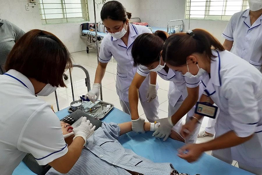 Các điều dưỡng đang cố gắng cho một bệnh nhân tâm thần uống thuốc khi người này không chịu hợp tác. Ảnh: TRẦN NGỌC