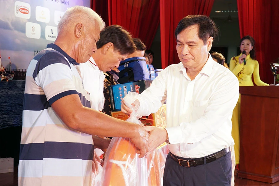 Ông Phan Xuân Thủy, Phó Trưởng ban Tuyên giáo Trung ương, đang trao các phần quà có ý nghĩa thiết thực của chương trình đến ngư dân Ninh Thuận. Ảnh: BẢO PHƯƠNG