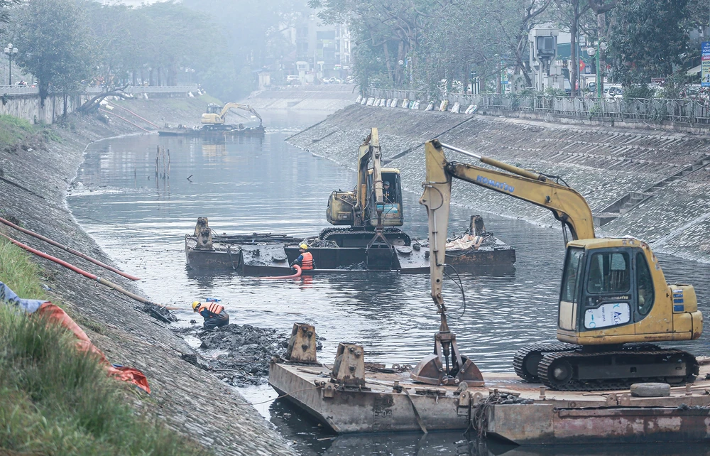 Công nhân của Công ty TNHH một thành viên Thoát nước Hà Nội đang thu gom bùn thải, nạo vét lòng sông Tô Lịch. Ảnh: Phi Hùng