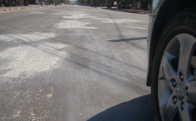 Bột đá xay được rải lên những đoạn đường bị chảynhựa tránh gây nguy hiểm cho xe cộ qua lại- Ảnh: Văn Định