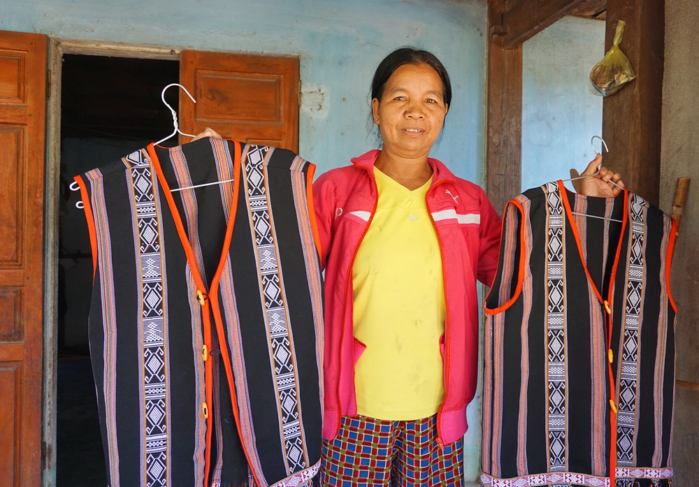 Nghệ nhân Y Mứk giới thiệu hai chiếc áo thành phẩm, hoa văn bắt mắt. Ảnh: LK.