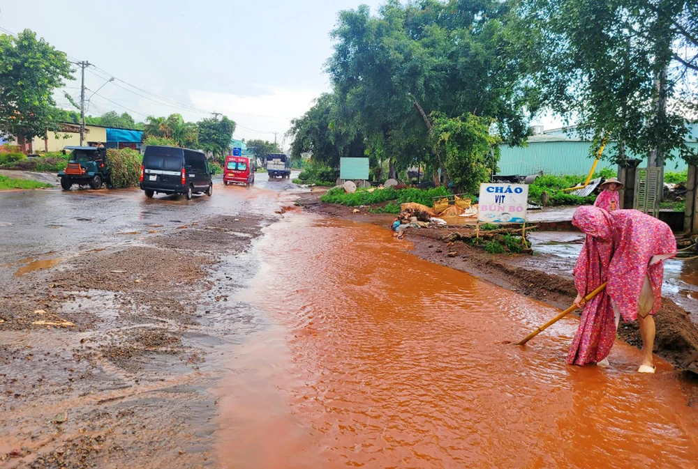 Trận mưa chiều 7-7, người dân xã Tân Bình ra đường tháo nước tránh ngập.