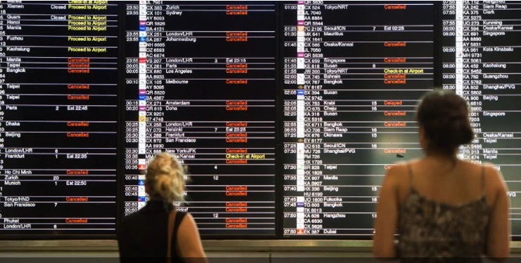 Hành khách theo dõi bảng hiển thị danh sách các chuyến bay bị hũy và bị hoãn lại ở Hong Kong. Ảnh: AFP