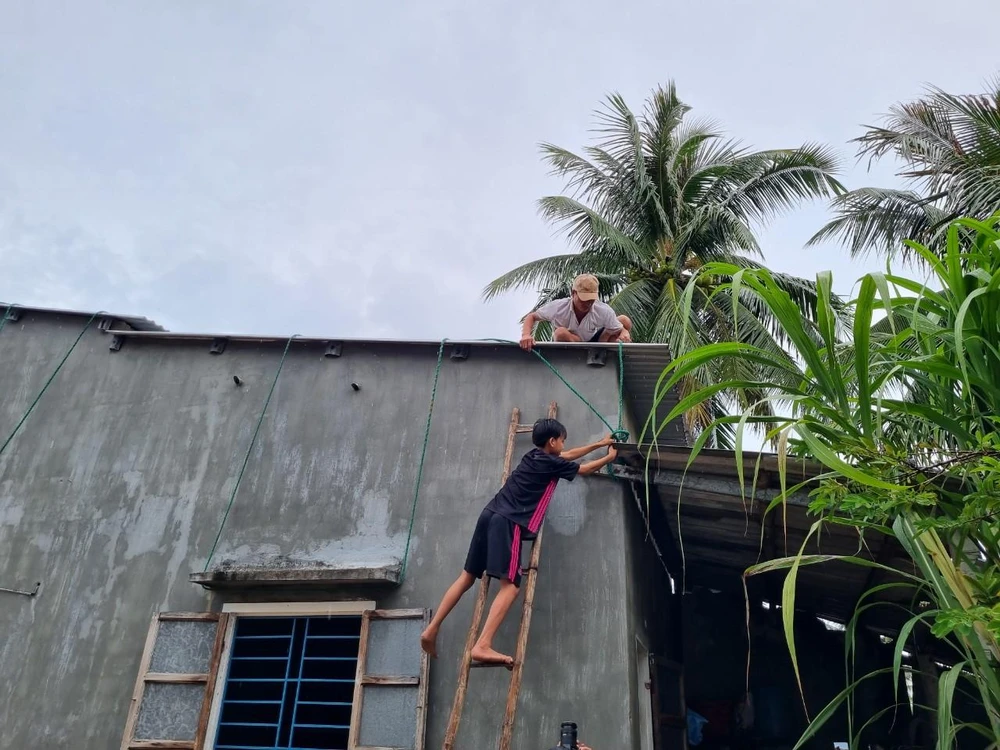 Ông Huỳnh Hữu Đạt (45 tuổi, ngụ xã Tam Hải) kéo dây đè lên trần nhà, hai đầu buộc chặt vào vật cứng. Ảnh: THANH NHẬT