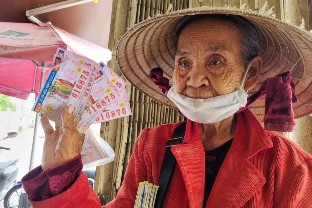 Bà Chính cầm tám tờ vé số bị kẻ gian sửa ngày để nhận thưởng. Ảnh: TN