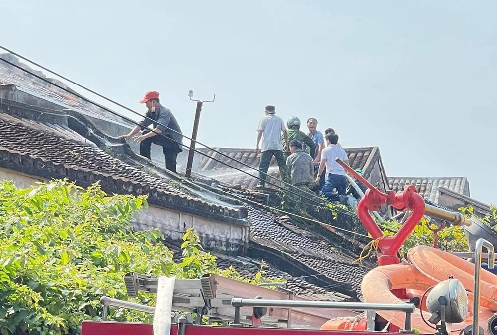 Lực lượng chức năng leo lên mái nhà để dập lửa. Ảnh: TN