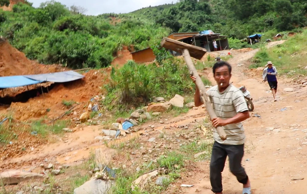 Một người cầm búa bằng gỗ lao vào đòi hành hung phóng viên. Ảnh: TN