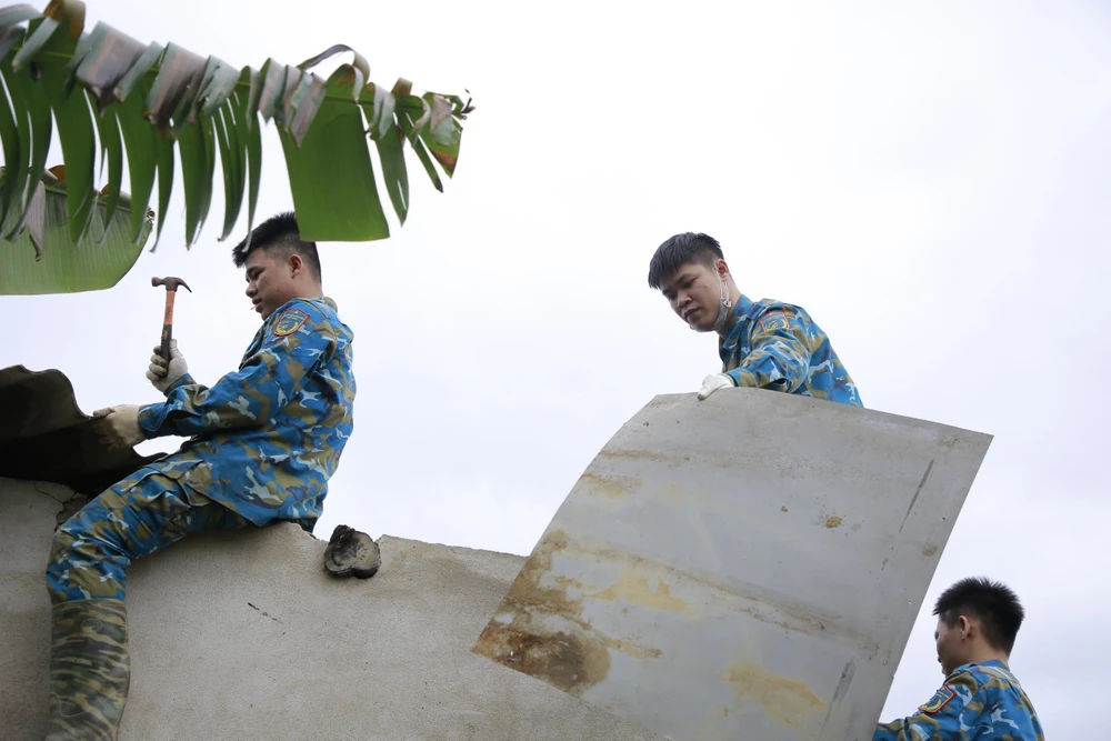 Các chiến sĩ Sư đoàn Không quân 372 sửa lại nhà cho người dân bị thiệt hại do vụ máy bay Su-22 rơi hôm 9-1. Ảnh: TN