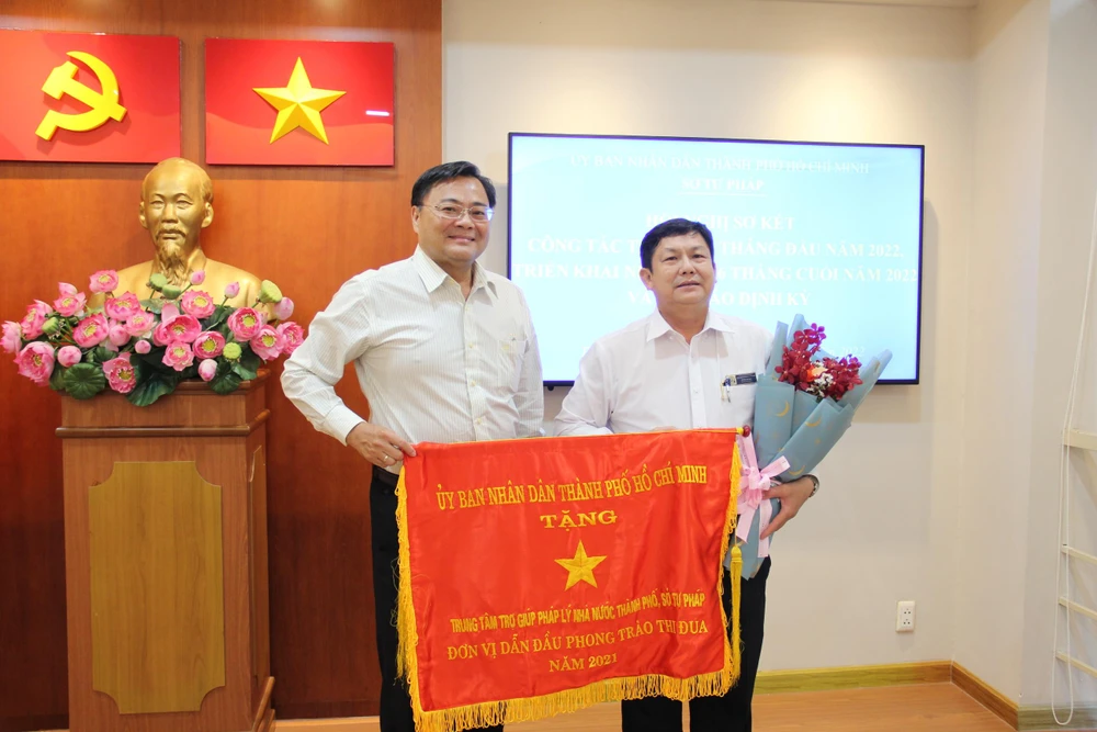 Ông Huỳnh Tấn Đạt, Giám đốc Trung tâm trợ giúp pháp lý Nhà nước tại TP,HCM đón nhận Cờ thi đua của UBND TP.HCM. Ảnh: TRÚC PHƯƠNG