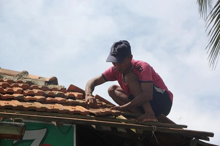 Chồng chị Quế đang sửa lại mái nhà sau bão. Ảnh: NGÔ QUANG