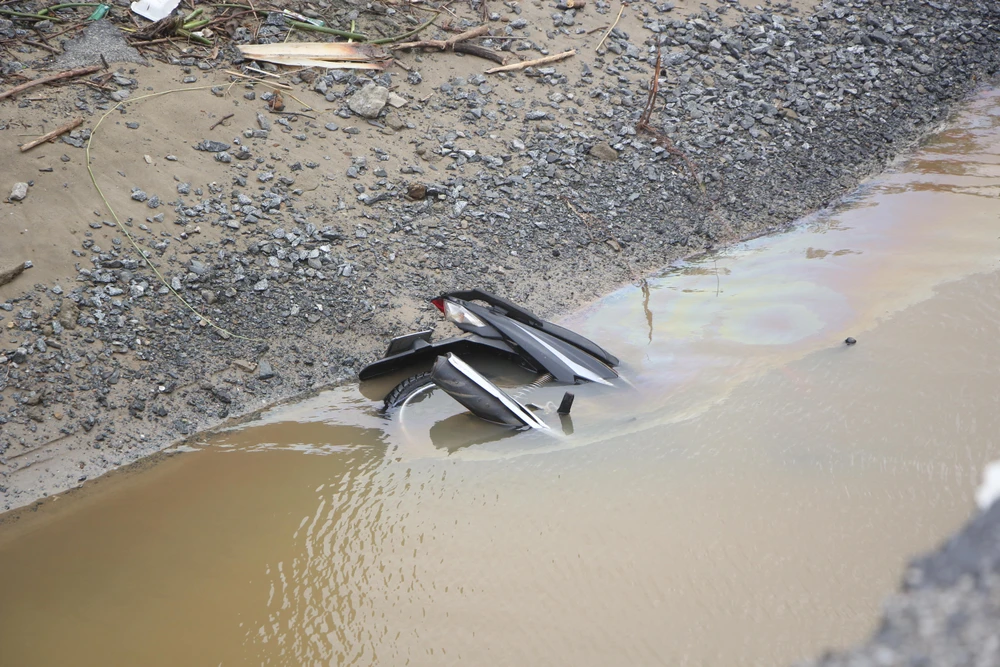 Chiếc xe máy nằm lọt thỏm dưới điểm sụt lún-Ảnh: NGÔ QUANG