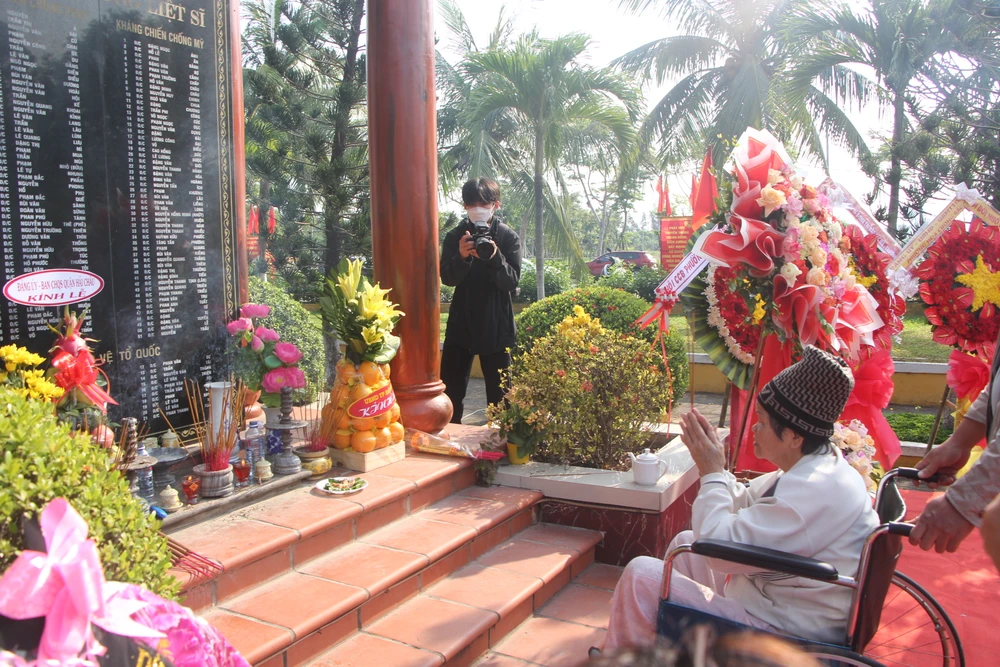 Cụ bà Lê Thị Lan ngồi xe lăn đến thắp hương 64 chiến sỹ hy sinh. Ảnh: NGÔ QUANG