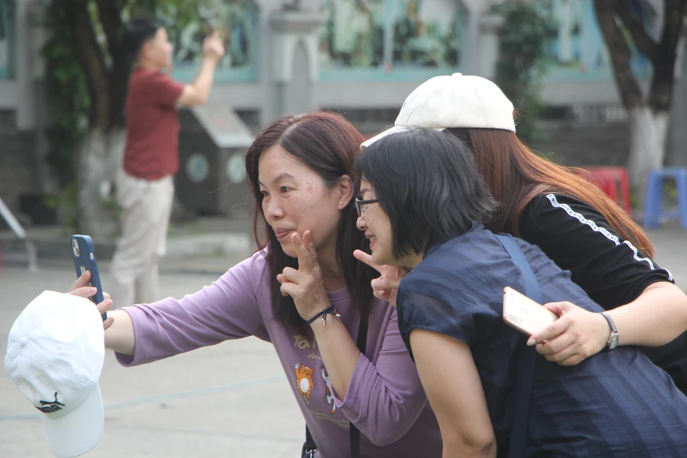 Các du khách tranh thủ checkin tại nhà thờ Con Gà.Ảnh: NGÔ QUANG
