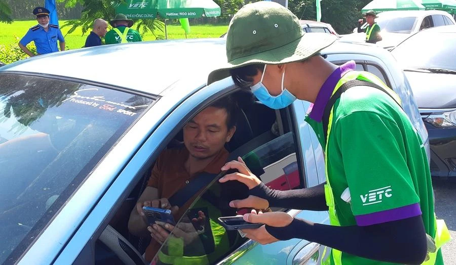 Nhân viên dán thẻ ETC hướng dẫn chủ phương tiện sử dụng tài khoản giao thông. Ảnh: V.LONG