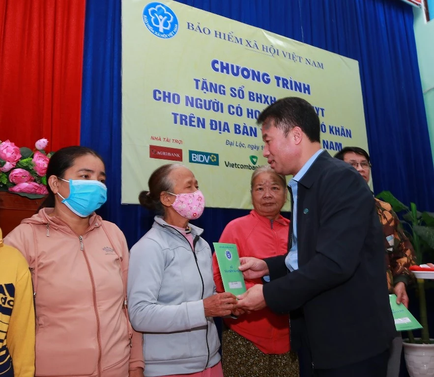 Lãnh đạo BHXH Việt Nam tặng sổ BHXH cho người dân. Ảnh: VLONG